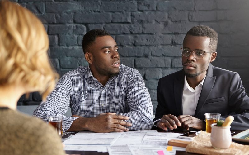Recruitment and human resources concept. Two doubtful African-American recruiters interviewing unrec Recruitment and human resources concept. Two doubtful African-American recruiters interviewing unrec